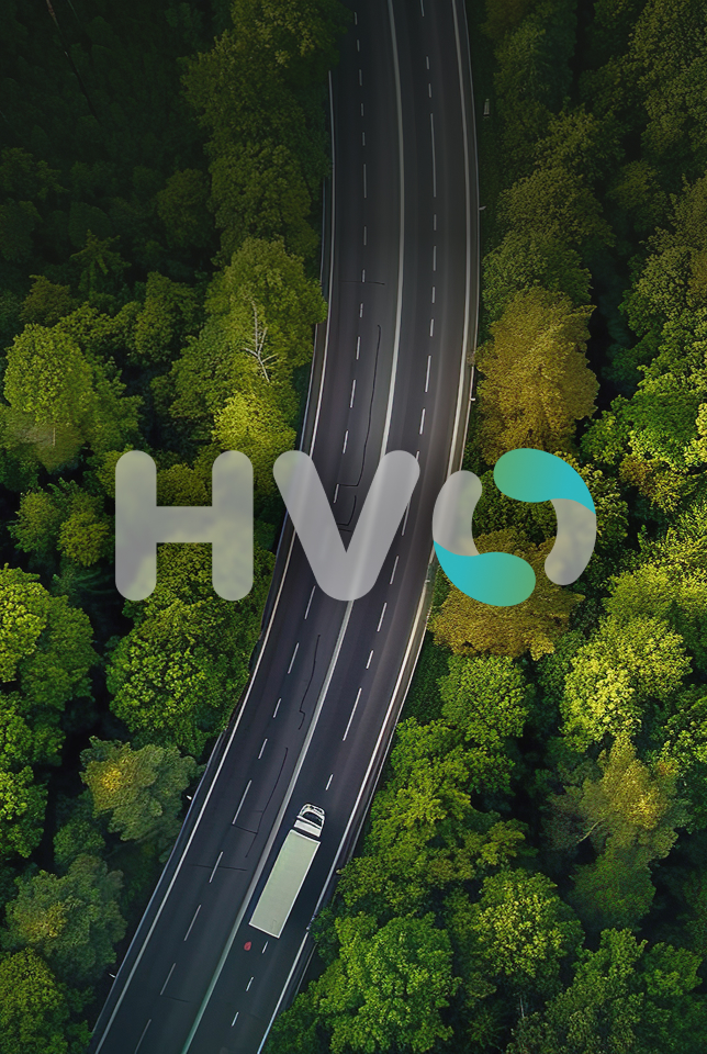 Scritta HVO in sovrimpressione su una strada immersa in un bosco verde vista dall'alto, per il biocombustibile Vega Carburanti